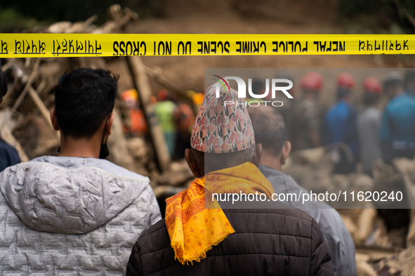 Family members wait to identify the recovered bodies of bus passengers buried in a landslide in Jhyaple Khola, Dhading District, Nepal, on S...