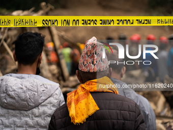 Family members wait to identify the recovered bodies of bus passengers buried in a landslide in Jhyaple Khola, Dhading District, Nepal, on S...