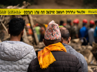 Family members wait to identify the recovered bodies of bus passengers buried in a landslide in Jhyaple Khola, Dhading District, Nepal, on S...