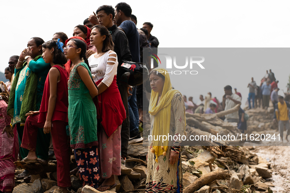 Spectators watch as the rescue teams conduct search operations at Jhyaple Khola, Dhading District, Nepal, on September 29, 2024, after passe...