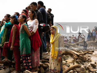 Spectators watch as the rescue teams conduct search operations at Jhyaple Khola, Dhading District, Nepal, on September 29, 2024, after passe...