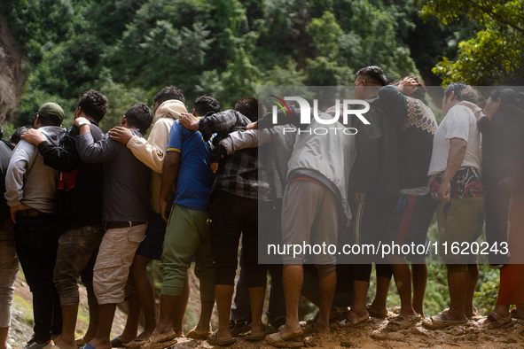 Spectators watch as the rescue teams conduct search operations at Jhyaple Khola, Dhading District, Nepal, on September 29, 2024, after passe...