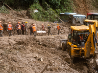 Rescue teams recover the dead body of bus passengers buried in a landslide in Jhyaple Khola, Dhading District, Nepal, on September 29, 2024....