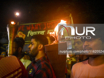 Doctors march with burning torches and shout slogans during a protest against the rape and murder of a PGT woman doctor at Government-run R...