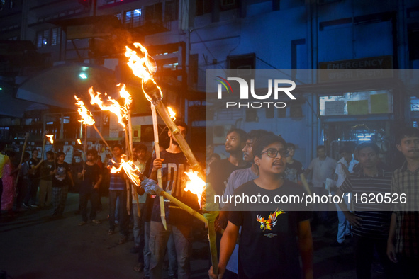 Doctors march with burning torches and shout slogans during a protest against the rape and murder of a PGT woman doctor at Government-run R...