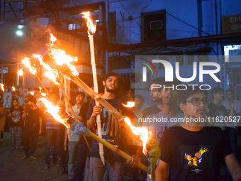 Doctors march with burning torches and shout slogans during a protest against the rape and murder of a PGT woman doctor at Government-run R...