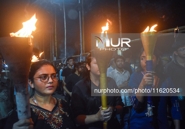 Doctors march with burning torches and shout slogans during a protest against the rape and murder of a PGT woman doctor at Government-run R...