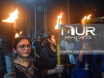 Doctors march with burning torches and shout slogans during a protest against the rape and murder of a PGT woman doctor at Government-run R...