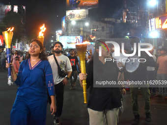 Doctors march with burning torches and shout slogans during a protest against the rape and murder of a PGT woman doctor at Government-run R...