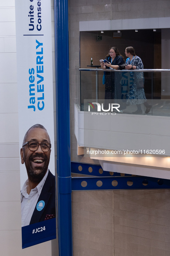 Delegates stand next to a James Cleverly banner at the Conservative Party Conference at the International Conference Centre in Birmingham, E...