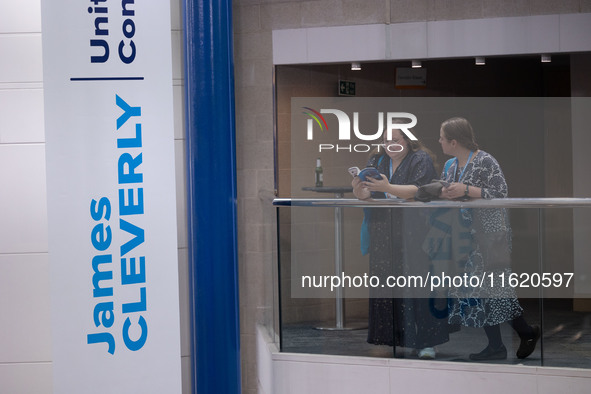 Delegates stand next to a James Cleverly banner at the Conservative Party Conference at the International Conference Centre in Birmingham, E...