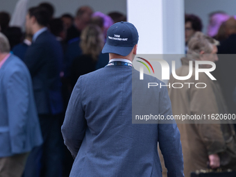 One of Tom Tugendhat's team wears a ''TOM I'M A TUGEND-HAT'' hat backwards at the Conservative Party Conference at the International Confere...