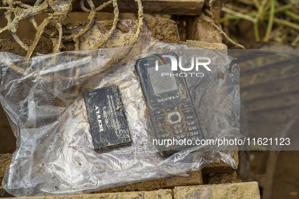 A damaged mobile phone is found while cleaning mud in the residential area along the Nakhu River bank in Lalitpur, Nepal, on September 29, 2...