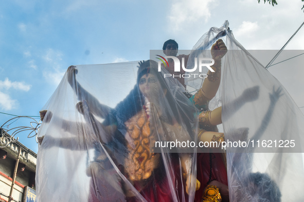 Laborers cover a Durga idol with plastic to protect it from rain on a truck for transport to a pandal, or a temporary platform, ahead of the...