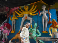 An old woman passes next to a half-made Durga idol ahead of the Durga Puja festival in Kolkata, India, on September 29, 2024. (