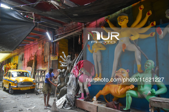 A person cleans a road next to a half-made Durga idol in Kolkata, India, on September 29, 2024. 