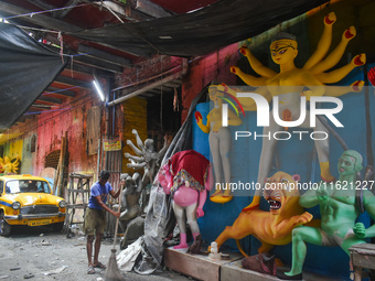 A person cleans a road next to a half-made Durga idol in Kolkata, India, on September 29, 2024. (