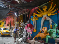 A person cleans a road next to a half-made Durga idol in Kolkata, India, on September 29, 2024. (