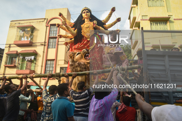 Workers load a Durga idol onto a truck for transport to a pandal, or a temporary platform, ahead of the Durga Puja festival in Kolkata, Indi...