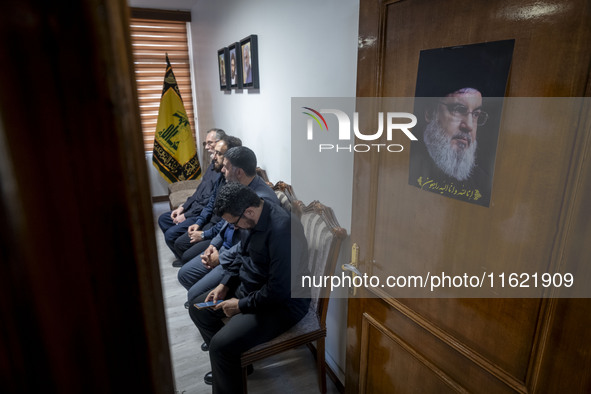 Unidentified men sit next to a portrait of Lebanon's Hezbollah Secretary General, Hassan Nasrallah, at the Hezbollah representative office d...