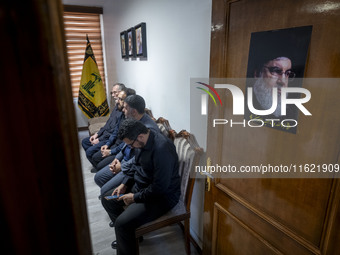 Unidentified men sit next to a portrait of Lebanon's Hezbollah Secretary General, Hassan Nasrallah, at the Hezbollah representative office d...