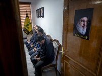 Unidentified men sit next to a portrait of Lebanon's Hezbollah Secretary General, Hassan Nasrallah, at the Hezbollah representative office d...