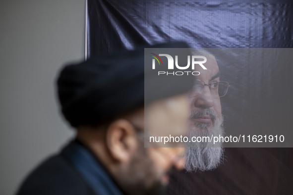 An unidentified cleric walks past a portrait of Lebanon's Hezbollah Secretary General, Hassan Nasrallah, at the Hezbollah representative off...