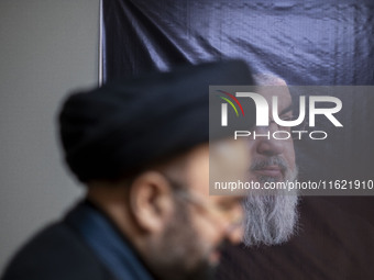 An unidentified cleric walks past a portrait of Lebanon's Hezbollah Secretary General, Hassan Nasrallah, at the Hezbollah representative off...