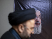 An unidentified cleric walks past a portrait of Lebanon's Hezbollah Secretary General, Hassan Nasrallah, at the Hezbollah representative off...