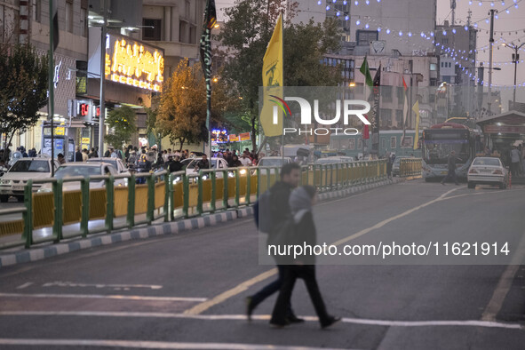 Iranian youths walk under a flag of Lebanon's Hezbollah that hangs on an avenue to commemorate Hezbollah Secretary General Hassan Nasrallah,...