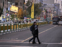 Iranian youths walk under a flag of Lebanon's Hezbollah that hangs on an avenue to commemorate Hezbollah Secretary General Hassan Nasrallah,...