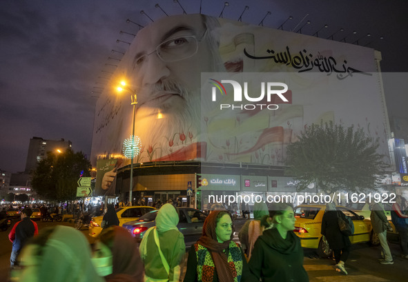 Iranian people walk under a giant banner featuring a portrait of Lebanon's Hezbollah Secretary General, Hassan Nasrallah, in downtown Tehran...