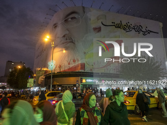 Iranian people walk under a giant banner featuring a portrait of Lebanon's Hezbollah Secretary General, Hassan Nasrallah, in downtown Tehran...