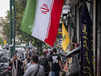 Iranian people walk past an Iranian flag and a flag of Lebanon's Hezbollah, displayed on a sidewalk to commemorate Hezbollah Secretary Gener...