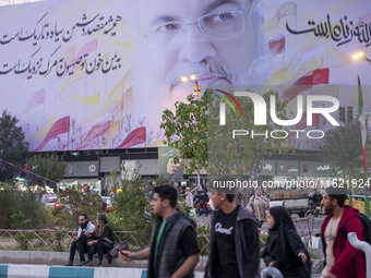 Iranian youths walk under a giant banner featuring a portrait of Lebanon's Hezbollah Secretary General, Hassan Nasrallah, in downtown Tehran...