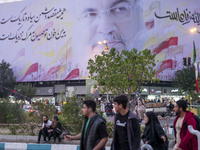 Iranian youths walk under a giant banner featuring a portrait of Lebanon's Hezbollah Secretary General, Hassan Nasrallah, in downtown Tehran...