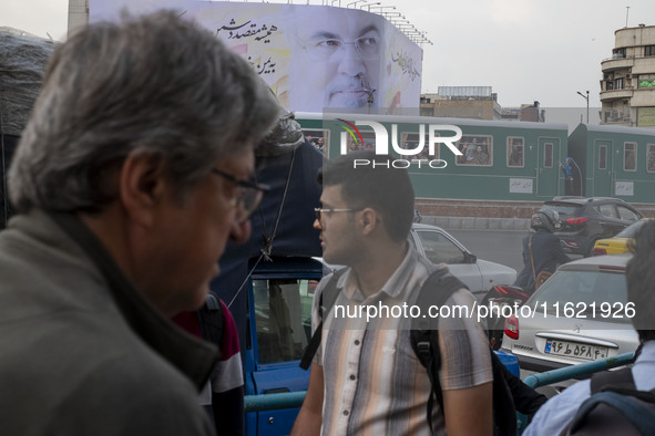 Iranian people walk under a giant banner featuring a portrait of Lebanon's Hezbollah Secretary General, Hassan Nasrallah, in downtown Tehran...