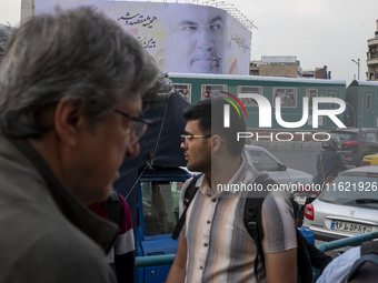 Iranian people walk under a giant banner featuring a portrait of Lebanon's Hezbollah Secretary General, Hassan Nasrallah, in downtown Tehran...