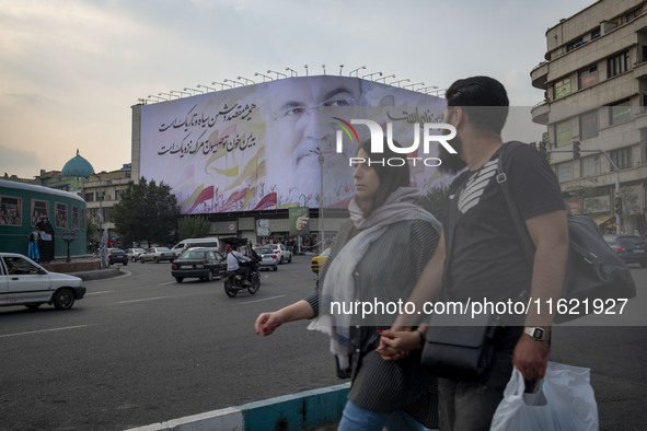 Iranian youths walk past a giant banner featuring a portrait of Lebanon's Hezbollah Secretary General, Hassan Nasrallah, who was killed in a...