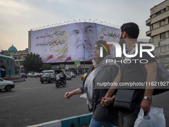 Iranian youths walk past a giant banner featuring a portrait of Lebanon's Hezbollah Secretary General, Hassan Nasrallah, who was killed in a...