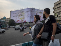 Iranian youths walk past a giant banner featuring a portrait of Lebanon's Hezbollah Secretary General, Hassan Nasrallah, who was killed in a...