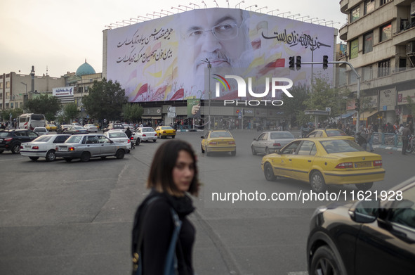 A young Iranian woman walks under a giant banner featuring a portrait of Lebanon's Hezbollah Secretary General, Hassan Nasrallah, who was ki...