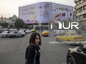 A young Iranian woman walks under a giant banner featuring a portrait of Lebanon's Hezbollah Secretary General, Hassan Nasrallah, who was ki...