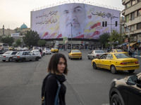 A young Iranian woman walks under a giant banner featuring a portrait of Lebanon's Hezbollah Secretary General, Hassan Nasrallah, who was ki...