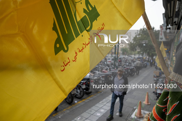 A young Iranian man walks under a Hezbollah flag displayed on a sidewalk to commemorate Hezbollah Secretary General Hassan Nasrallah, who wa...