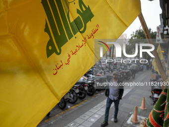 A young Iranian man walks under a Hezbollah flag displayed on a sidewalk to commemorate Hezbollah Secretary General Hassan Nasrallah, who wa...