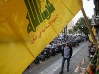 A young Iranian man walks under a Hezbollah flag displayed on a sidewalk to commemorate Hezbollah Secretary General Hassan Nasrallah, who wa...