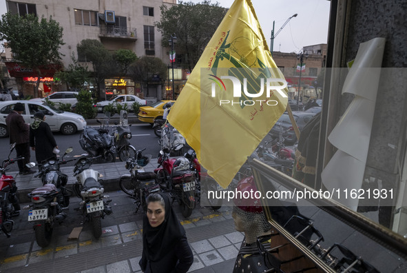 An Iranian woman walks under a Hezbollah flag displayed on a sidewalk to commemorate Hezbollah Secretary General Hassan Nasrallah, who was k...