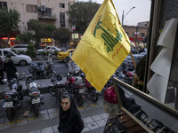 An Iranian woman walks under a Hezbollah flag displayed on a sidewalk to commemorate Hezbollah Secretary General Hassan Nasrallah, who was k...