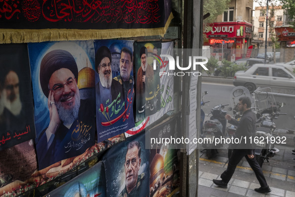 An Iranian man walks past posters featuring portraits of Lebanon's Hezbollah Secretary General, Hassan Nasrallah, and Iranian commander of t...